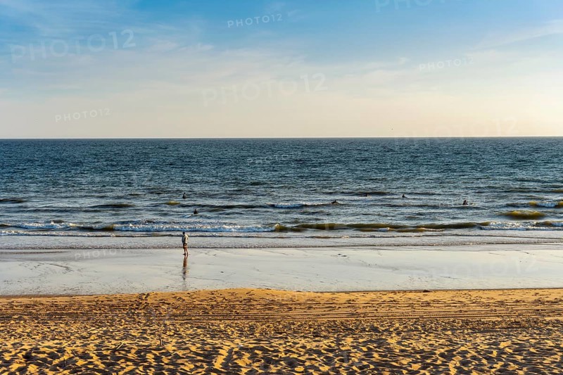 Surfers training skills in the ocean with their coach on the beach