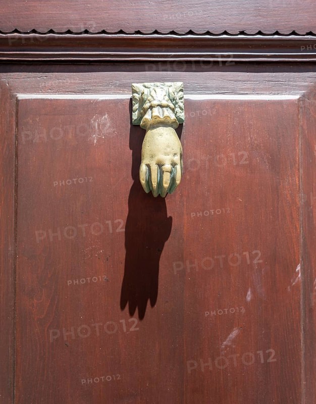 Door knocker in the shape of a hand on a brown door