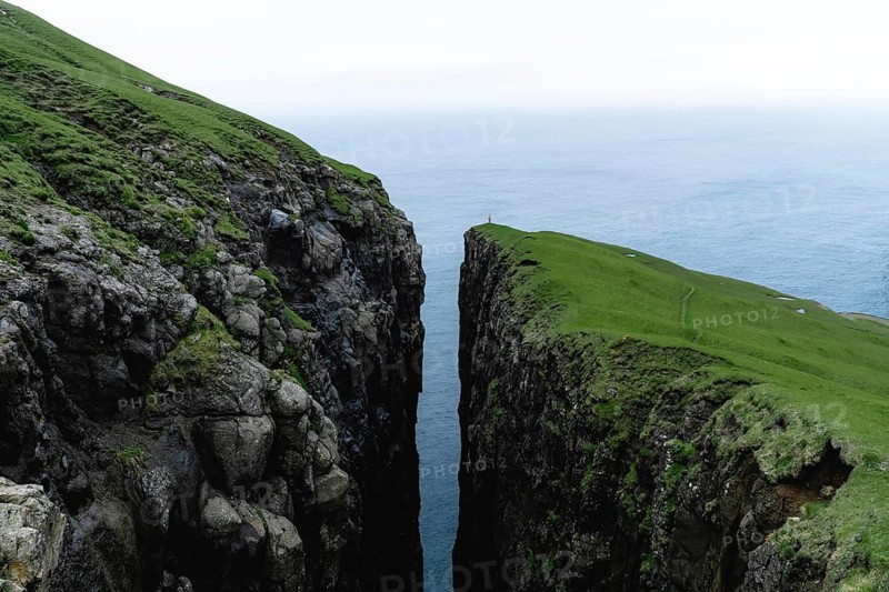 Small person standing on cliff with deep crevice
