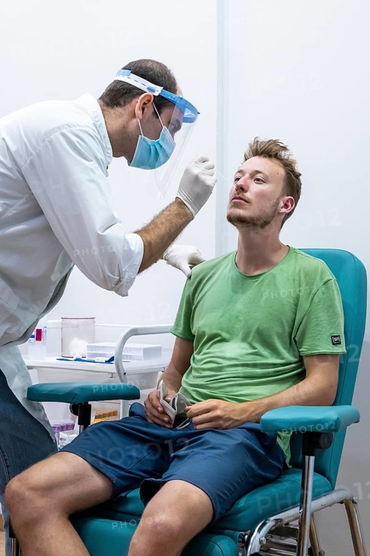 Doctor in protective clothing does an antigen test on a young man