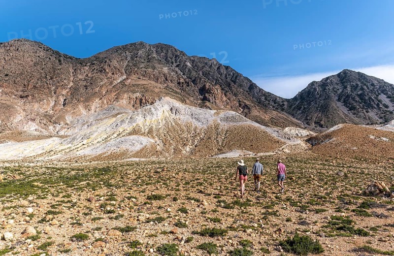 Three tourists hiking in a volcanic caldera with pumice fields
