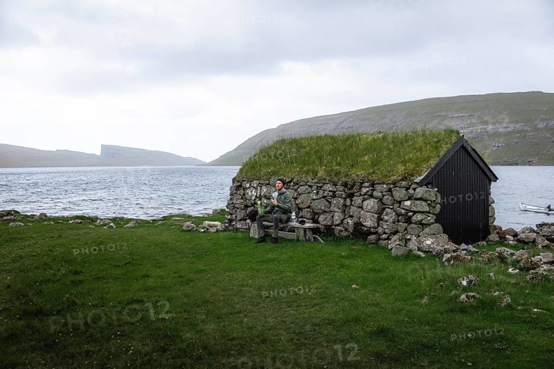 Hiker eating biscuits on a bench in front of a stone hut