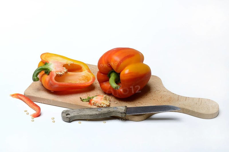 Yellow-red coloured peppers (Capsicum) on wooden board