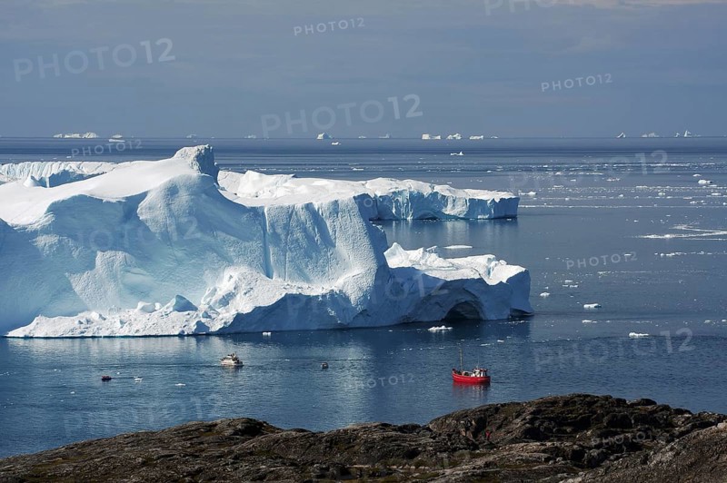 View of small fishing boat and bay with icebergs