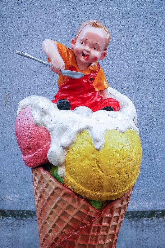 Advertising figure in front of an ice cream parlor: small child sitting in an ice cream cone