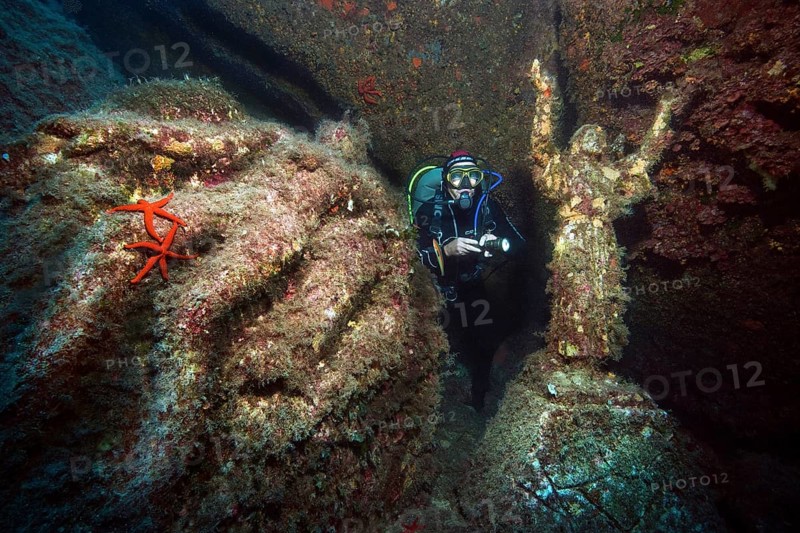 Diver looking at and illuminating statue of Christ with raised arms