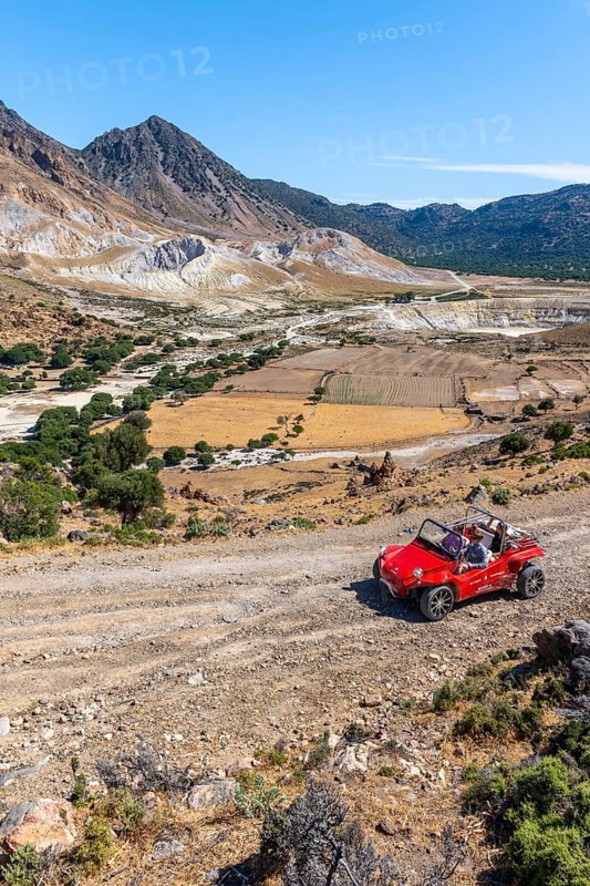 Tourists explore Nysiros with a red car on a gravel road