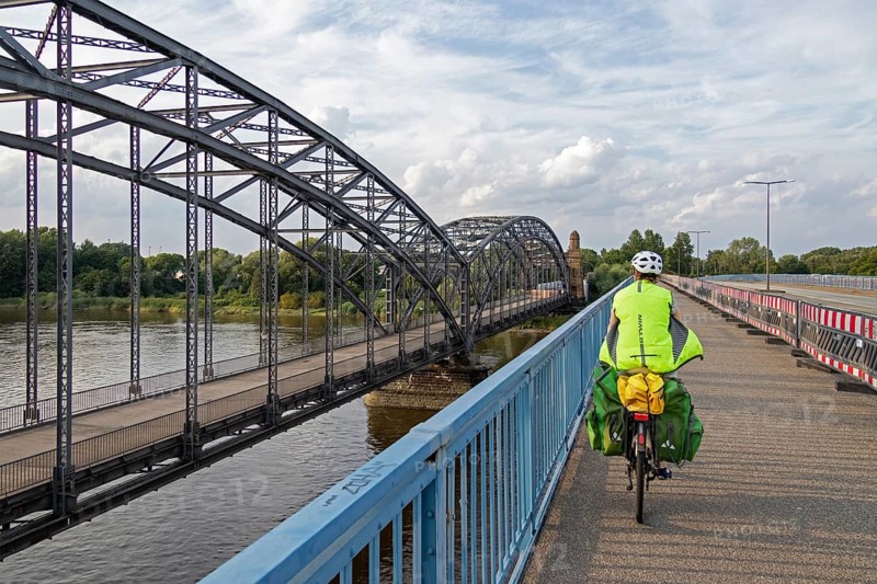 Woman riding her bicycle over bridge next to the Alte Harbruecker Elbbruecke