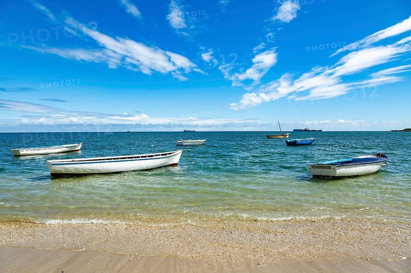 Fishing boats in turquoise green water on the beach at Bain des Dames