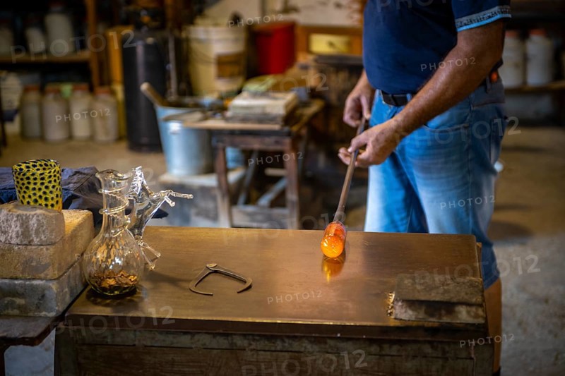 Working hot glass in the workshop of a glassblower