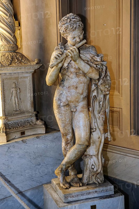 Statue in marble of child playing the flute