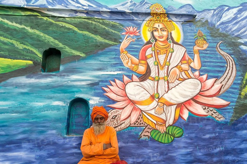 Sadhu in saffron robes in front of an image of a deity
