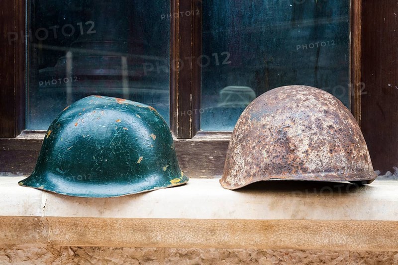 Soldiers' helmets displayed in front of a window