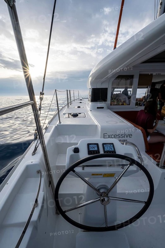 Steering wheel in the cockpit on the deck of a sailing catamaran in the evening light