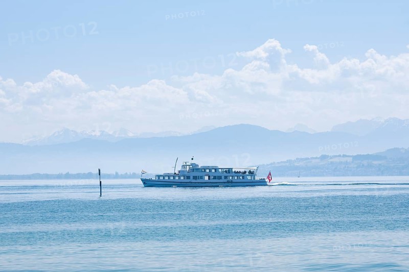 View from Arbon over the shimmering blue Lake Constance with a scheduled boat in sunny weather and blue sky in summer