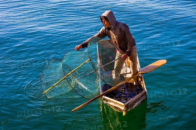 Fisherman with fish trap in his floating coffin