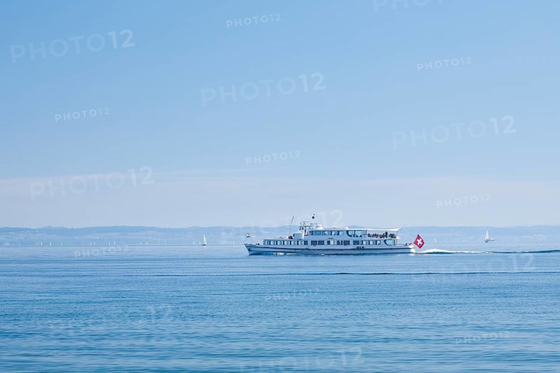 View from Arbon over the shimmering blue Lake Constance with a scheduled boat in sunny weather and blue sky in summer