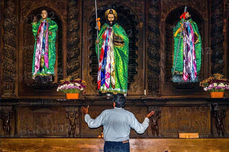 Shaman talking to wooden figures of the saints