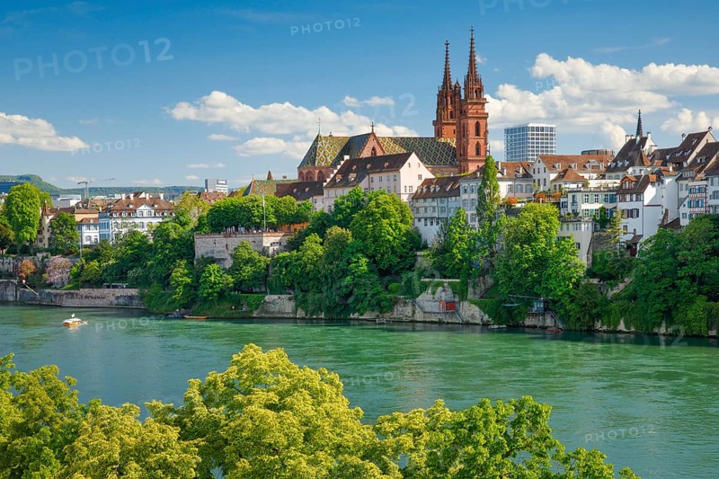 View of the Basel Cathedral in the middle of the old town of Basel with the turquoise Rhine River in the foreground