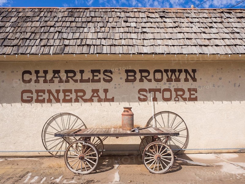 Old cart with rusty milk can in front of General Store