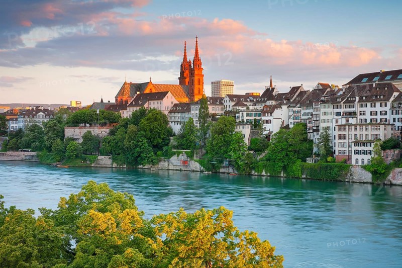 View of the Basel Cathedral in the middle of the old town of Basel with the turquoise Rhine River in the foreground