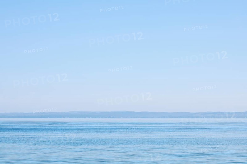 View from Arbon over blue shimmering Lake Constance in sunny weather and blue sky in summer
