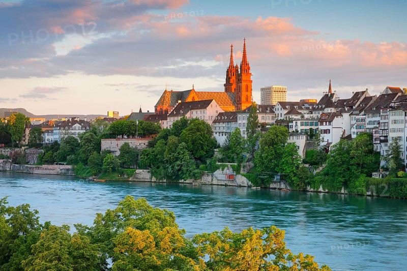 View of the Basel Cathedral in the middle of the old town of Basel with the turquoise Rhine River in the foreground