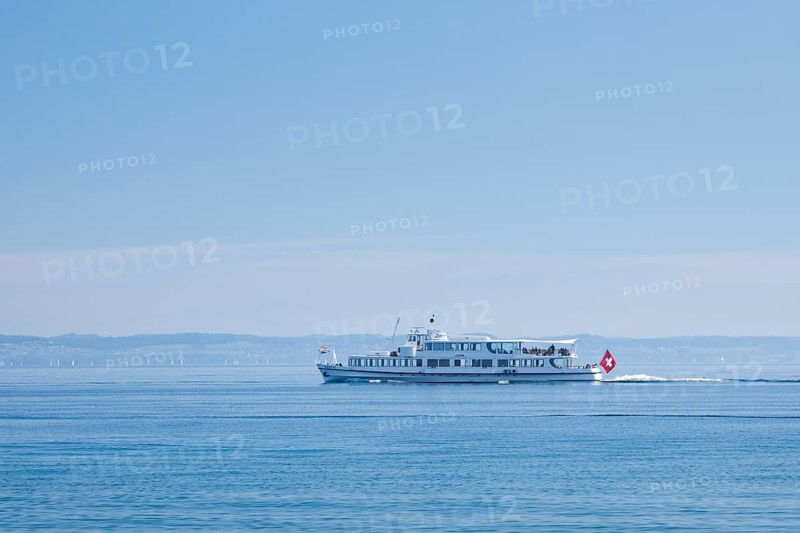 View from Arbon over the shimmering blue Lake Constance with a scheduled boat in sunny weather and blue sky in summer