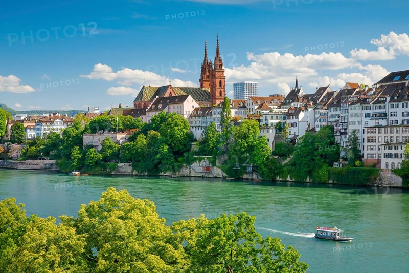 View of the Basel Cathedral in the middle of the old town of Basel with the turquoise Rhine River in the foreground