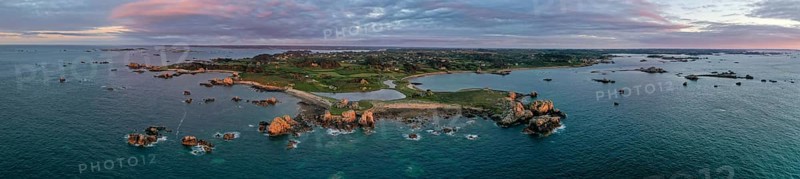 Panorama drone shot from the Atlantic Ocean onto the granite coast of Plougrescant with a view of the house between the rocks (Le gouffre de Plougrescant) at sunset
