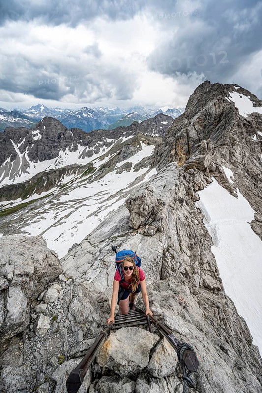 Hiker climbing metal ladder on rock