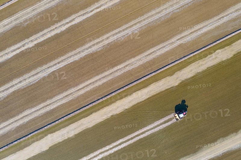 Tractor sowing rice seeds in a flooded rice field in May