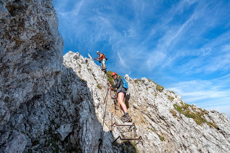 Mountaineers climbing a ladder on a secured via ferrata