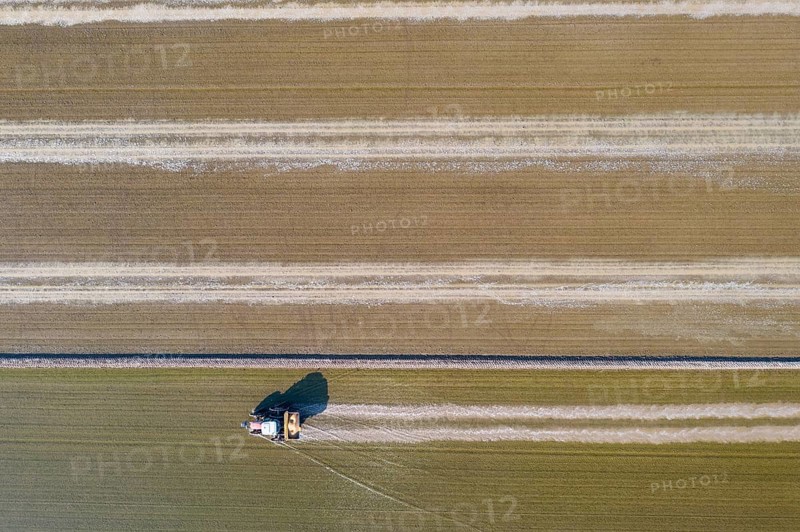 Tractor sowing rice seeds in a flooded rice field in May