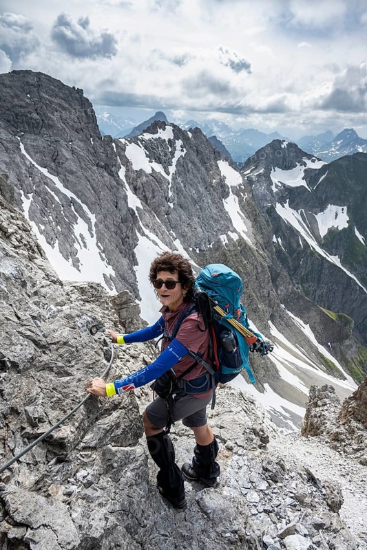 Mountaineer on a secured ridge trail with remnants of snow