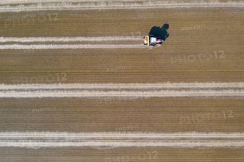 Tractor sowing rice seeds in a flooded rice field in May