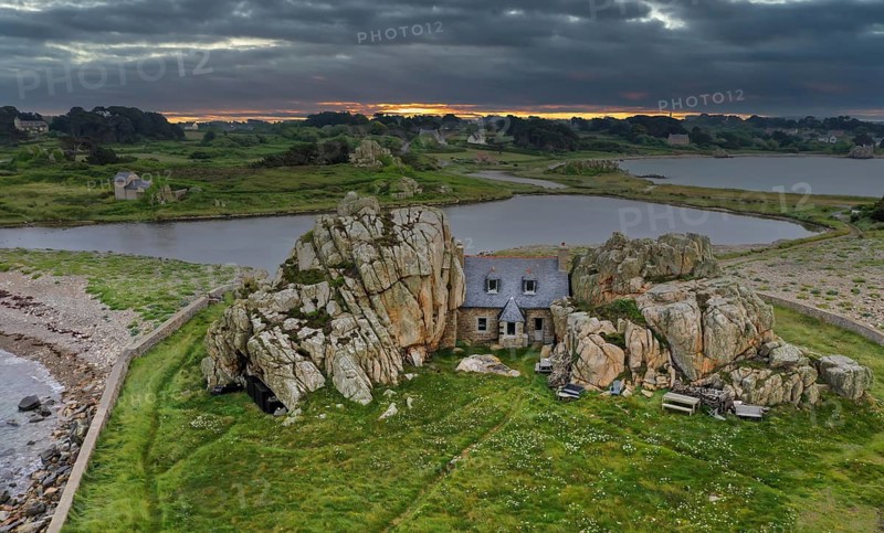 Drone shot from the Atlantic Ocean onto the house between the rocks (Le gouffre de Plougrescant) at sunset