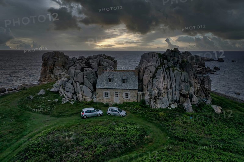 Drone shot from the mainland of the house between the rocks (Le gouffre de Plougrescant) with dramatic sky and the Atlantic Ocean