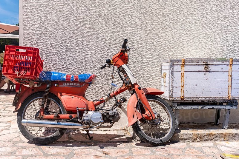 Old red scooter in front of a wall
