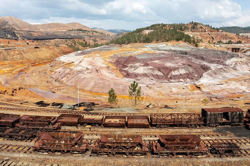 Disused wagons at the dramatically scarred landscape of mineral-rich ground and rock at the Rio Tinto mines