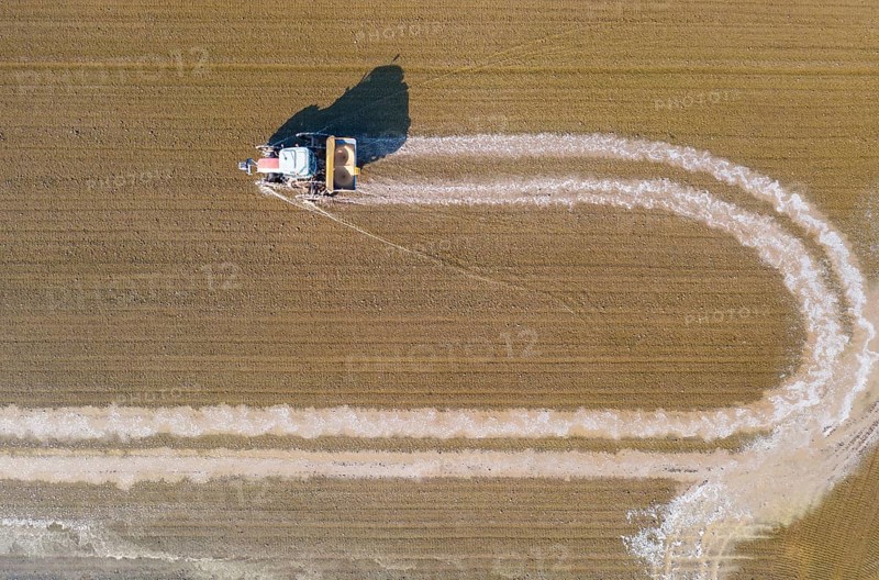 Tractor sowing rice seeds in a flooded rice field in May
