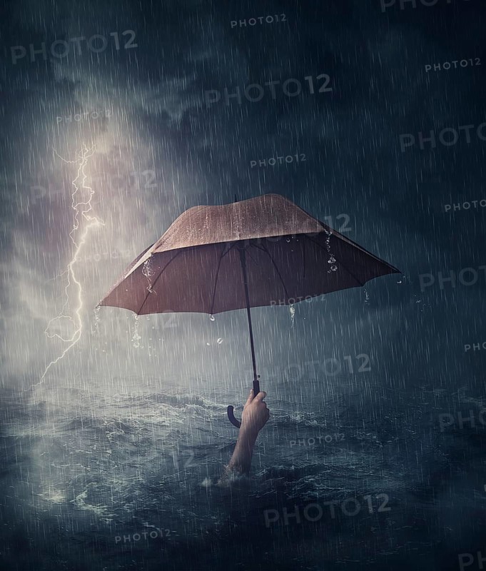 Human hand holding an umbrella sinking in the ocean. Surreal and dramatic scene of person drowning in the sea waters under the storm. Business despair and failure metaphor. Crisis problems concept