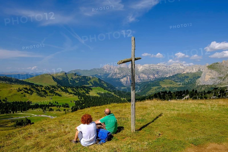 Hikers sitting at the summit cross at the Sella Pass