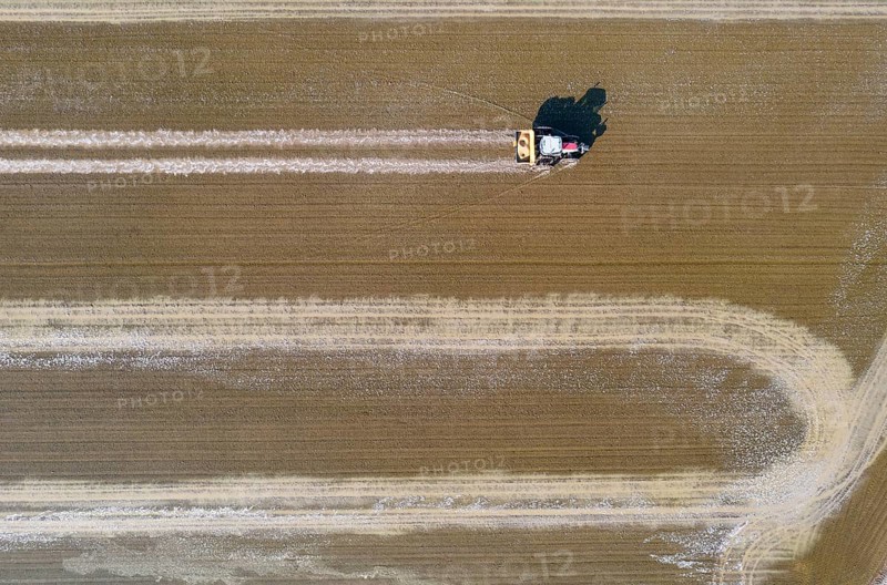 Tractor sowing rice seeds in a flooded rice field in May