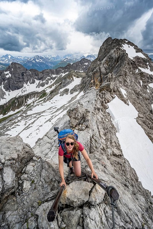 Hiker climbing metal ladder on rock
