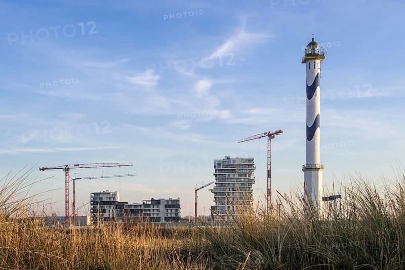 Lange Nelle lighthouse and new flats under construction for the Oosteroever real estate project in the port of Ostend on the Belgian North Sea coast
