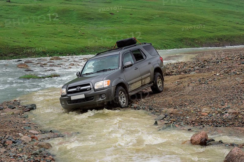 Off-road vehicle crossing a mountain river at Tosor Pass