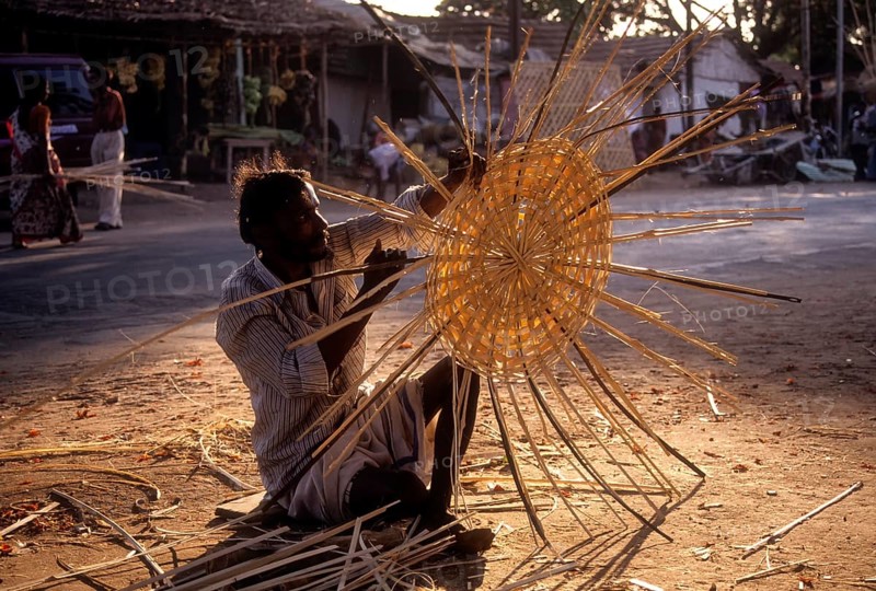 Basket maker weaving bamboo strips baskets
