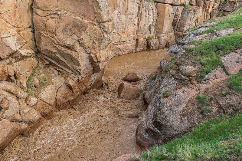 Muddy mountain river flowing through a narrow gorge