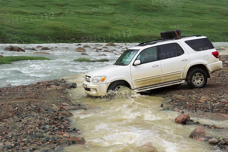Off-road vehicle crossing a mountain river at Tosor Pass